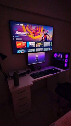 the computer desk has two monitors on it and is lit up with purple lights in the dark