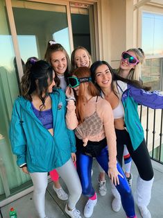 a group of girls standing next to each other in front of a door with their arms around one another