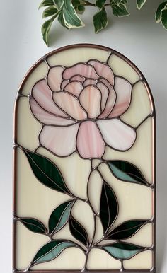 a stained glass window with a rose on it's side and green leaves in the background