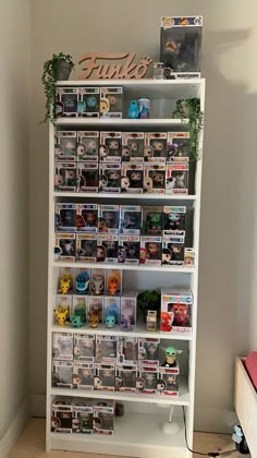a white book shelf filled with lots of books next to a wall covered in pictures