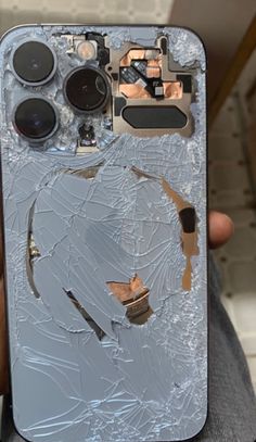 someone is holding up their phone with some broken glass on the front and back sides