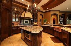 a large kitchen with marble counter tops and wooden cabinets, chandelier above the island