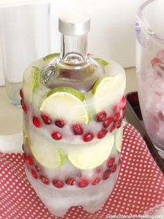a glass bottle filled with fruit and ice on top of a red checkered table cloth