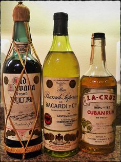 three different types of alcohol bottles on a counter top, one containing rum and the other containing an empty bottle