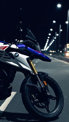 the motorcycle is parked on the side of the road at night time with its lights on