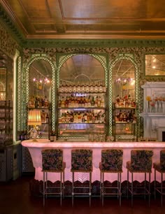 an ornately decorated bar with pink table cloths and chairs in front of it