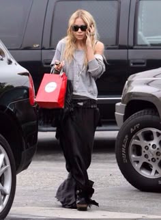 a woman is walking down the street talking on her cell phone and holding shopping bags