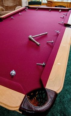 a pool table with several tools on it in a room filled with furniture and windows