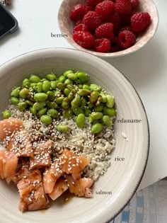 a white bowl filled with rice and meat next to raspberries on top of a table