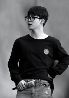 a young man with glasses is holding his hands on his hips