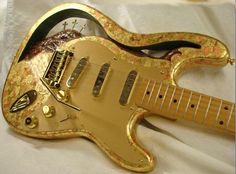 a gold colored guitar sitting on top of a white sheet