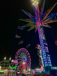 an amusement park at night with ferris wheel and rides