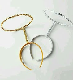 two necklaces with gold, silver and black beads on white surface next to each other