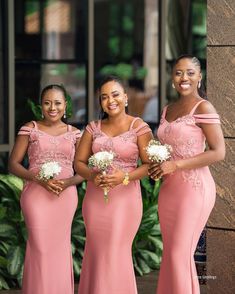 three bridesmaids in pink dresses posing for the camera with their bouquets on