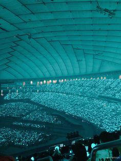 a large group of people sitting in an auditorium with lights on the ceiling and rows of seats