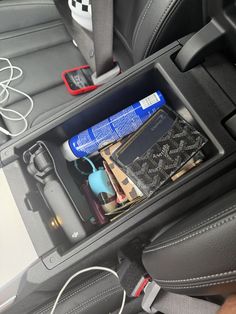an open compartment in the back seat of a car filled with electronics and other items