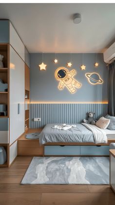 a bedroom with blue walls and white furniture, including a bed that has an astronaut motif on the wall