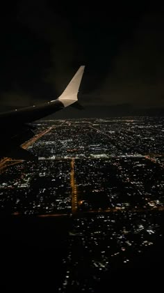 an airplane wing flying over the city at night