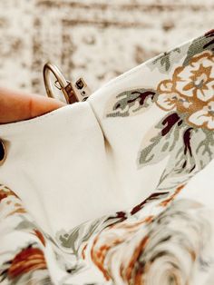 a person holding an open ring on top of a flowered cloth bag with their thumb in the other hand