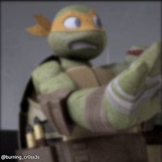 a stuffed turtle is sitting in a chair with his hand up to the side and eyes open