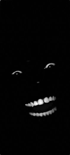 a black and white photo of a person's face in the dark with light coming from his mouth