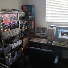 there are two computer monitors on the desk next to each other in front of a window