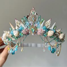 a tiara with seashells, pearls and other sea creatures is being held by a woman