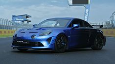 a blue sports car driving down a race track