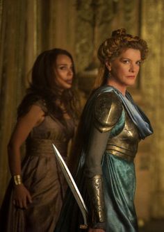 two women standing next to each other holding swords