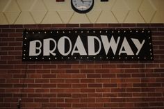there is a sign on the wall that says broadway with a clock in the background