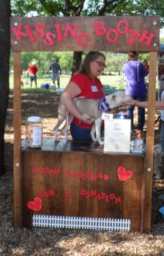 a woman standing behind a kiosk with a dog on it