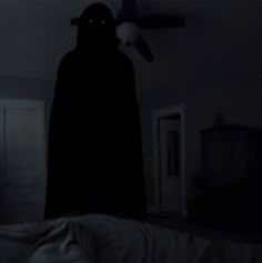 a person in a dark room with a light on and a bat hanging from the ceiling