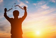 the silhouette of a man with his arms in the air, holding two balls and chains