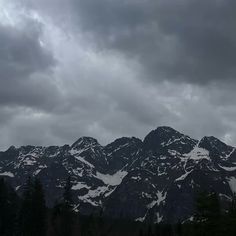 the mountains are covered in snow and clouds