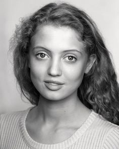 a black and white photo of a young woman with long hair, wearing a sweater
