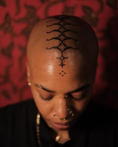 a woman with her head shaved up and tattoos on it's forehead, looking down