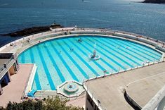 an aerial view of a large swimming pool in the middle of water with people standing around it