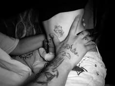 two people with tattoos on their stomachs holding each other's hands in the air
