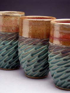 three ceramic cups sitting next to each other on a table