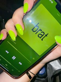a woman with bright green nails holding up her cell phone to show the app on it