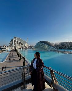 a woman standing on top of a metal railing next to a body of blue water