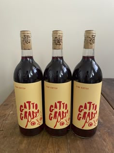 three bottles of wine sitting on top of a wooden table
