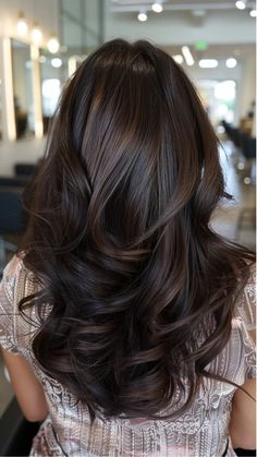 Long, wavy brunette hair with subtle highlights in a salon setting.