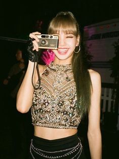 a woman holding up a camera in front of her face and wearing a black skirt