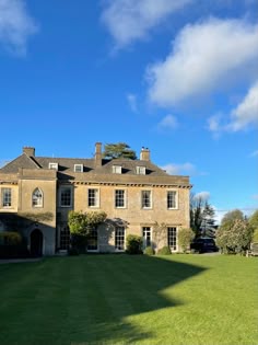 a large brown house sitting in the middle of a lush green field on a sunny day