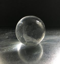 a clear glass ball sitting on top of a gray countertop next to a black wall