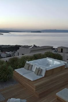 a hot tub sitting on top of a wooden deck next to the ocean at sunset