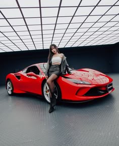a woman sitting on top of a red sports car