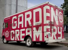 a red and white food truck parked on the side of the road next to a silo
