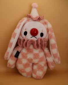 a pink and white stuffed animal with a red nose